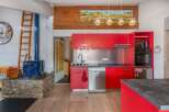 This stunning property boasts a modern kitchen with vibrant red cabinetry, stainless steel appliances, and a sleek countertop.