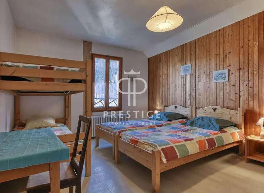 Cozy bedroom with wooden paneling and multiple beds, perfect for a family or group.