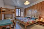 Cozy bedroom with wooden paneling and multiple beds, perfect for a family or group.
