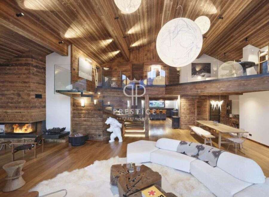 Experience luxury living in this stunning chalet, featuring a warm and inviting interior with exposed wooden beams and walls.