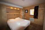 Cozy bedroom with wooden paneling and a comfortable bed.