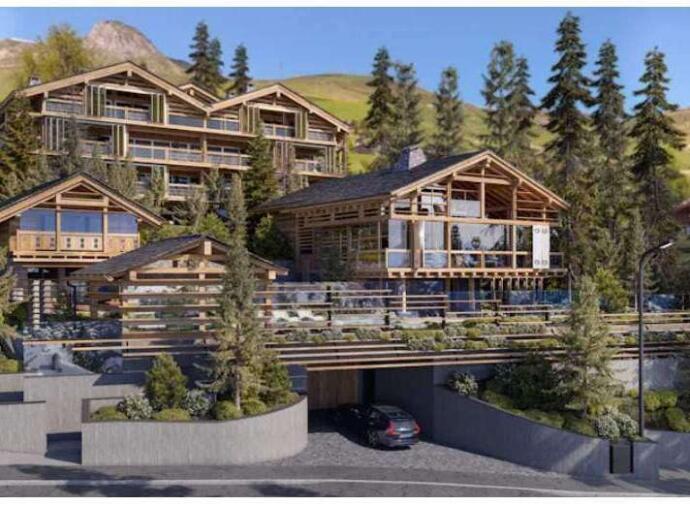 A modern multi-level wooden chalet with large windows and balconies, set in a mountain area surrounded by tall pine trees, with a car parked in the driveway.