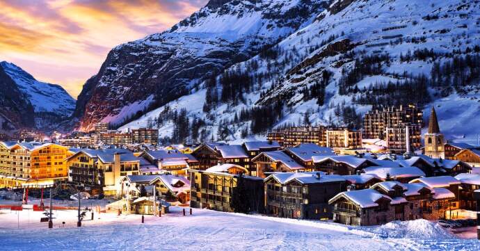 A picturesque snowy mountain village illuminated at dusk.