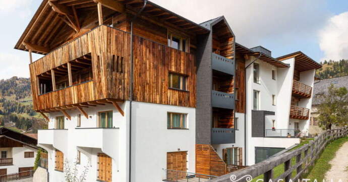 Modern building with white plaster and wooden paneling in a mountainous area.